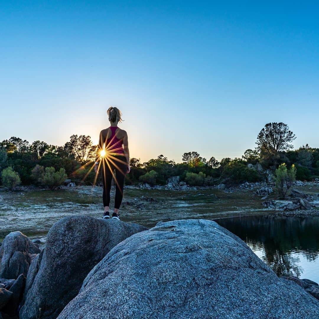 women standing on a rock next to a lake