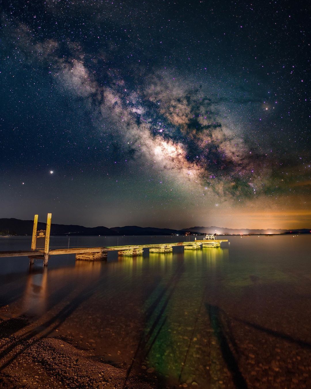 Photograph of starry night sky above pier extending into Lake Tahoe