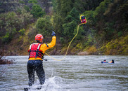 A firefighter tosses a rescue bag toward a swimmer in the American River 