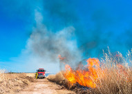 Wildfire burning grassland with fire engine on the attack