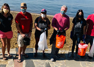 Photograph of people wearing face coverings and holding trash buckets on North Lake Tahoe lakeshore