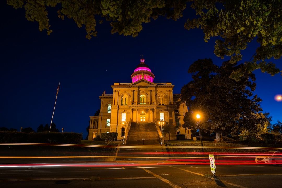 Photo of the Auburn Court House at night light up with pink lights. 