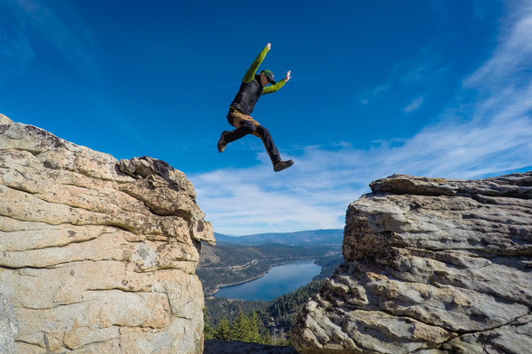 Man jumping between rocks with Donner Lake in the background