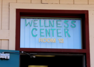 Painted sign above a schoolhouse door reading Wellness Center