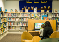 mother and toddler sitting at computer in a library