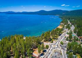 Drone footage of Kings Beach North Lake Tahoe - clear blue water next to row of trees and downtown corridor