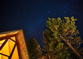 Night sky, corner of a cabin, and a tree. Image taken from below looking up.