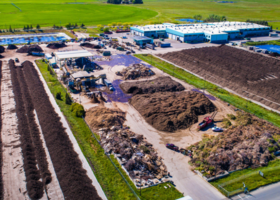 Waste management site with dirt piles and a warehouse