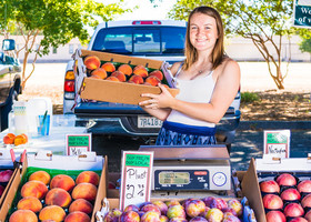 Woman holding crate of peaches at the farmer's market