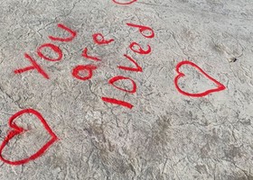 Red sand on the sidewalk spells out, you are loved to signify human trafficking awareness month