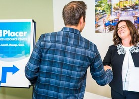 A man and woman shake hands in front of Placer County's Business Resource Center