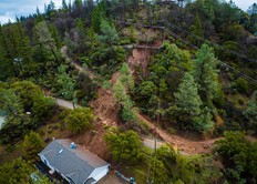 Aerial view of a mudslide crossing a road and colliding with a home in Colfax, California