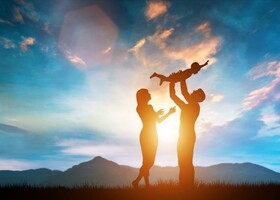 Silhouette of parents holding child in air