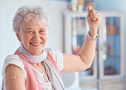 Elderly woman with a band aid on arm smiles after getting vaccinated