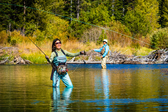 Woman wading in water fly fishes in Lake Tahoe
