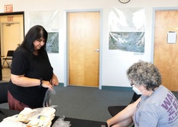woman standing on counter putting on a glove while another older woman sits