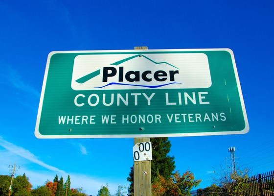 Road sign reading: Placer County line. Where we honor veterans