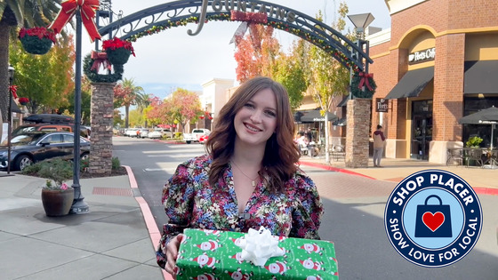 Young woman smiles while holding a locally shopped gift
