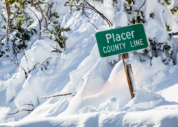 A snow-buried sign reading "Placer County Line"