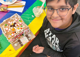 Smiling boy builds a candy-covered gingerbread house