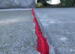 Red sand placed in a sidewalk crack