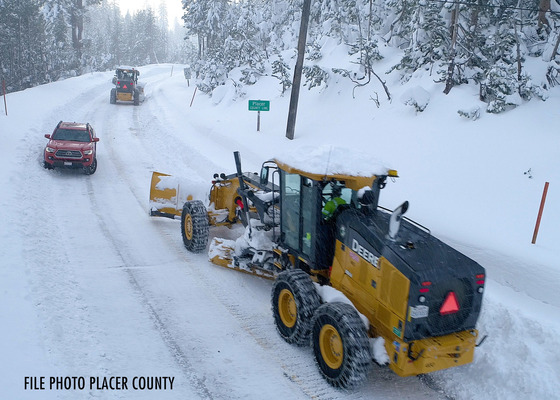 Snow plow clears snow-covered road in Placer County