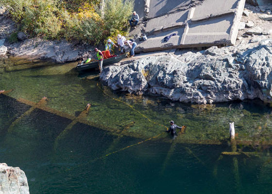 An aerial view of a collapsed bridge beneath the surface of a river