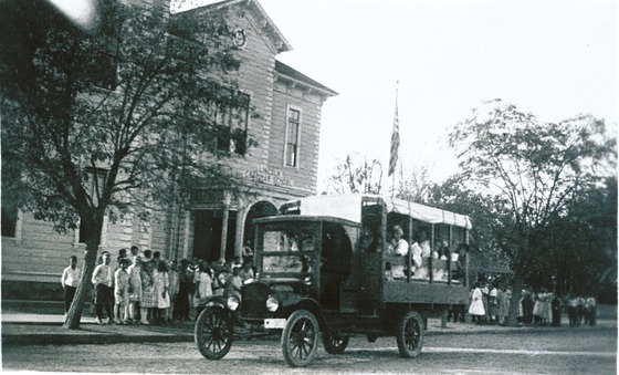 School bus in front of school 1920