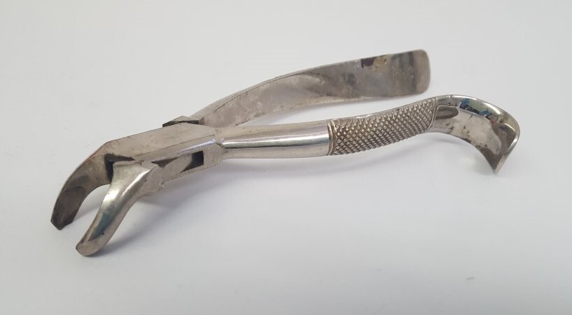A dental extractor resting on a white background 
