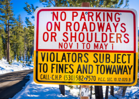  An image of a parking restrictions roadway sign in front of a snowy road in eastern Placer.