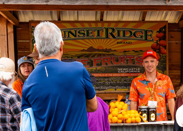 Mandarin vendors standing in front of patrons at a fruit stand