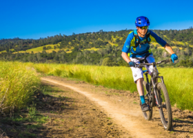 Man riding a mountain bike on a single-track trail, hills in the background