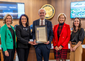 Placer County’s five Board of Supervisors members pose with one holding a framed document