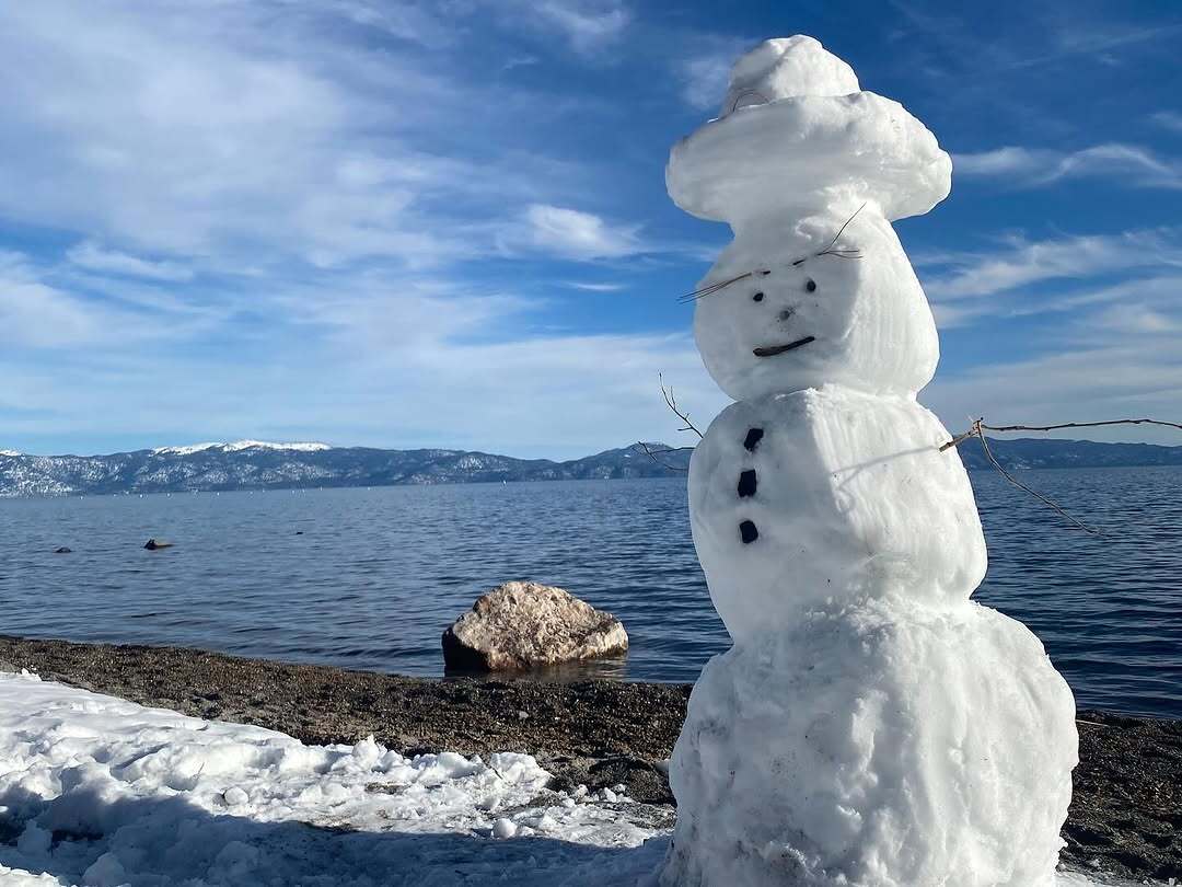 The Photo of the Week featuring a snowman with a top hat of snow next to Lake Tahoe.