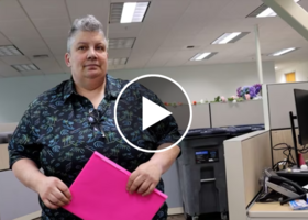 Woman holding pink folder, with video play button overlay