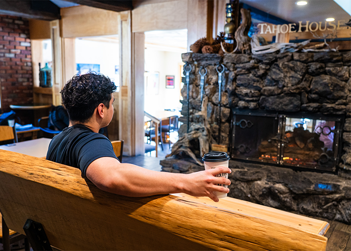 An image of a person holding a cup of coffee on a bench in a coffee shop