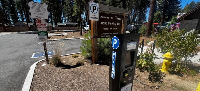 An image of a black pay station with blue signage in front of the Christmas Tree Parking Lot in Kings Beach.
