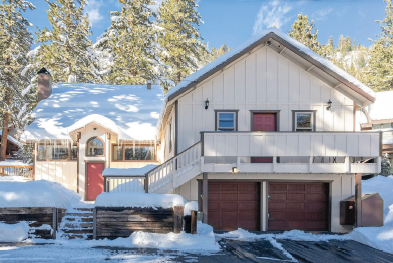 A white house with a garage in the snow.