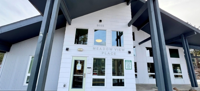 An exterior image of a large white building with gray text noting Meadow View Place