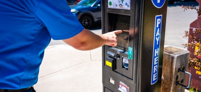 An image of a person in a blue shirt pushing a button on a paid parking meter in Kings Beach.