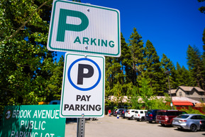 A paid parking sign with a black letter p on it with a blue circle in front of Brook Ave. in Kings Beach.