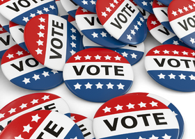 Image of numerous red, blue and white “Vote” buttons with stars on them.