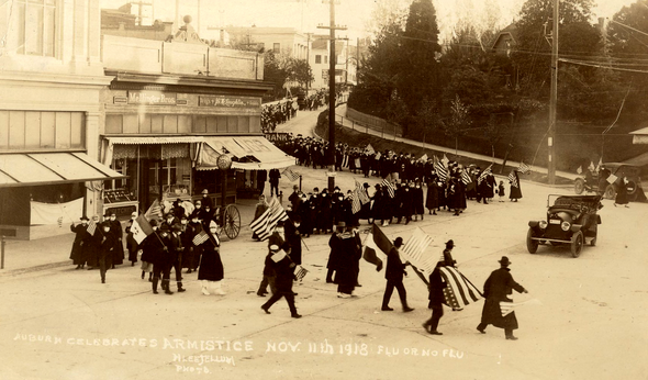 A massive crowd of people marching down main street holding American flags.