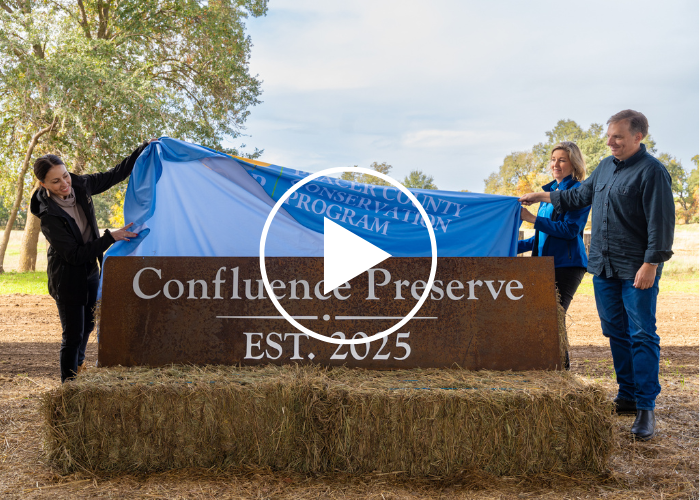 Three people unveil a sign that says Confluence Preserve