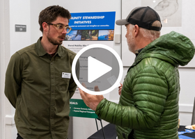 Two people in green clothing talking inside the North Tahoe Event Center at the county’s Discover and Discuss event.