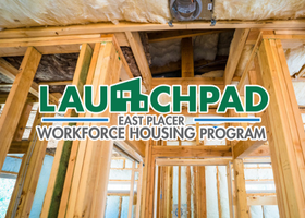 The Launchpad logo in green and black outlined in white on top of a new construction ADU project showing interior wood framing.