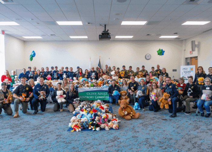 ozens of first responders and OAAC members standing around a table full of stuffed animals