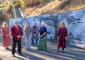 Artists pose in front of mural in Colfax