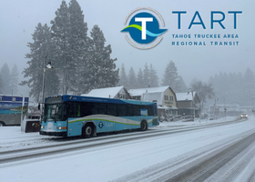 A blue Truckee Tahoe Area Regional Transit bus stops on a snow-covered road in North Lake Tahoe with the TART logo.