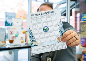 A person holding a Winter Book Bingo Card